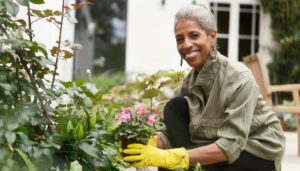 elder woman smiles in her garden as she plants flowers