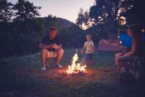 Father with children making a camping fire in the backyard.